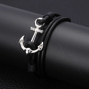 Detail of silver anchor pendant on black braided multi-layer leather nautical bracelet