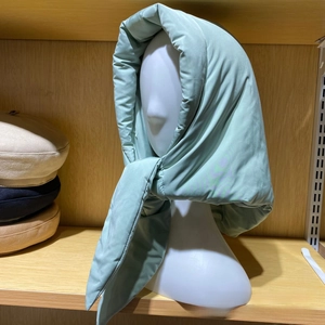 Macro detail of a light green insulated quilted hood scarf on a white mannequin stand