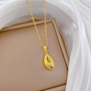 Macro detail of gold necklace with oval pendant featuring five colorful gemstones