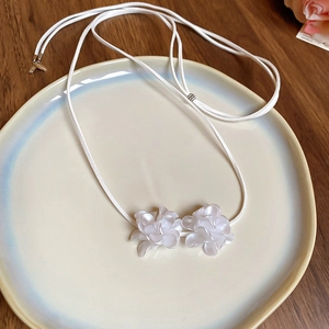 Détail d'un collier de fleurs blanches en résine sur une assiette en céramique