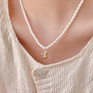 Close-up of a vintage 925 silver necklace with white pearls and a golden rosebud pendant