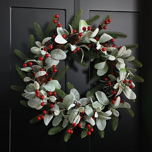 Christmas wreath with red berries, pine cones and frosted leaves on black door