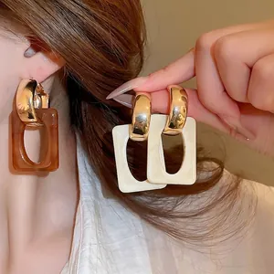 Elegant geometric resin drop earrings in tortoiseshell and cream on a golden metal ring