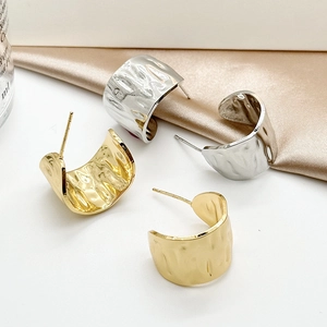 Detailed macro view of gold and silver chunky teardrop earrings with hammered texture finish