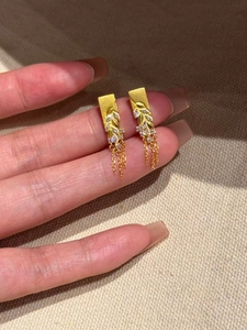 Macro detail of gold wheat ear earrings with sparkling cubic zirconia and long fringe tassels