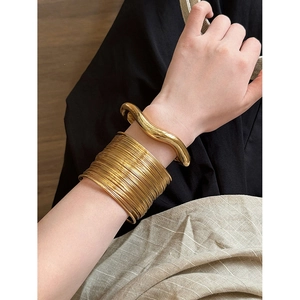 Detail of minimalist wavy and multi-layered gold arm cuffs on a model arm
