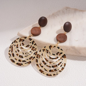 Détail du pendentif en acrylique léopard et texture en bois sur les boucles d'oreilles