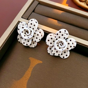 Gros plan de boucles d'oreilles fleurs en acrylique blanc à pois noirs dans un coffret