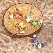 Close-up of bohemian beach necklaces with shells and starfish on a wooden plate and sand