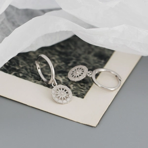 Macro detail of S925 sterling silver hoop earrings with radial sunburst compass charms
