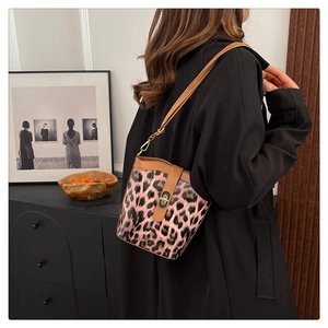 Detail of pink leopard bucket bag with brown strap and metal clasp on a female model