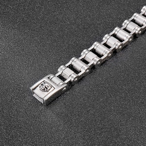 Detail of stainless steel bike chain bracelet featuring a punk skull buckle and knurled texture