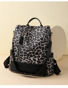 Detail of grey leopard print backpack with black PU leather base and metal zipper pocket