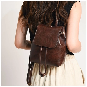 Detail view of the vintage brown leather backpack with drawstring closure on model