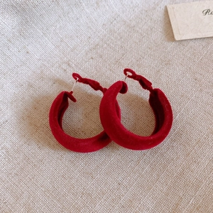 Macro view of vintage red velvet C-shaped earrings with metallic stud details