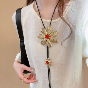 Detail of flower bolo tie with gold metal petals and vibrant red gemstone inlay