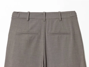 Detailed view of grey trousers featuring belt loops and double-piped back pockets texture