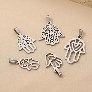Macro view of five silver stainless steel hollow Hamsa hand charms on beige fabric
