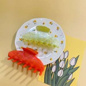 Detail of large acrylic hair claws in green mesh and solid orange for stylish styling