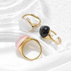 Detailed view of adjustable gold-plated rings with oval white, black, and pink stones