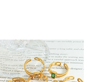 Macro shot of gold-plated twisted double-line rings with emerald green and white gemstones