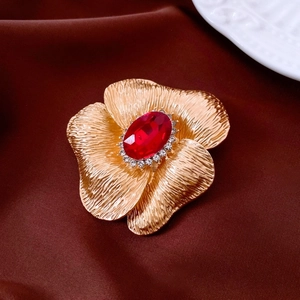 Close-up of vintage flower brooch with red oval gemstone and white rhinestones detail