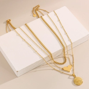 Dettaglio di collane d'oro a strati con pendenti a forma di occhio e cuore su cubi bianchi