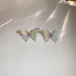 Macro detail of butterfly earrings with blue gradient wings and sparkling crystal accents