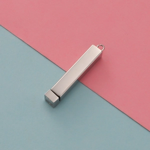 Detail of silver mirror-finish stainless steel rectangular pendant on pink and blue background