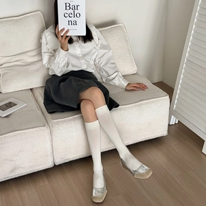 Close-up of white ribbed knee-high socks paired with silver leather flats and a grey skirt
