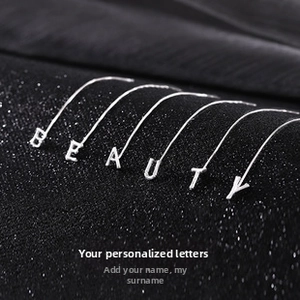 Detailed view of silver minimalist bamboo style letter earrings spelling BEAUTY on black background