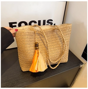 Close-up of handmade straw tote bag with textured weave and wooden bead tassel detail