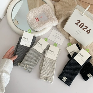 Detail of grey and beige ribbed knit socks with brand tags in a cozy home setting