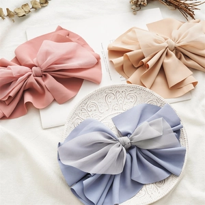 Close-up of elegant large fabric bow hair clips in pink beige and blue chiffon colors