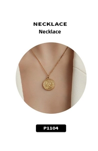 Detailed close-up of a 18k gold coin pendant necklace with embossed portrait on a thin chain