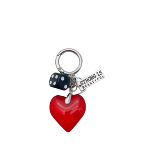 Fashion keychain with red heart charm, black dice, and engraved metal tag on white background