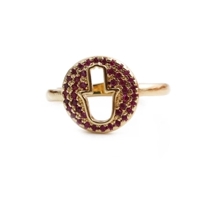 Macro detail of gold Hamsa Hand ring featuring a red pavé-set zircon halo