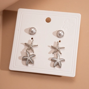Detail of six-piece earring set with faux pearls and silver starfish studs on white card