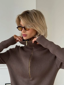 Detail of a dark brown half-zip knit sweater showing ribbed texture and gold zipper