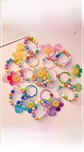 Colorful sunflower beaded keychain with heart charms and macaron pearls on pink background