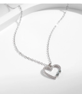 Detail of s925 silver heart necklace with blue infinity symbol and sparkling zircon stones
