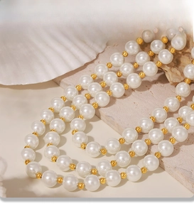 Close-up of a layered shell pearl necklace with gold-plated beads on a white shell and stone
