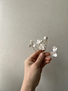 Detail of handmade ceramic flowers and pearls on golden bridal hair forks set