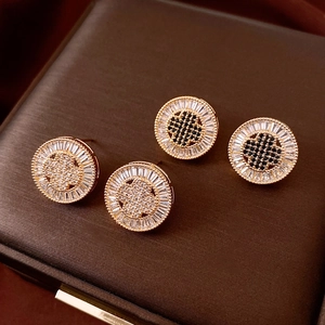 Macro shot of 18k gold plated round earrings with square zircons and clover motif