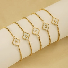 Detailed view of five gold clover bracelets with letters A-E on a white display stand