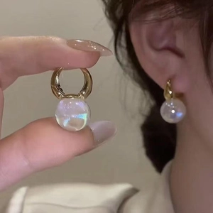 Close-up of elegant gold pearl earring being held and shown on a model's ear