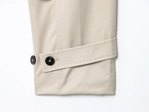 Dettaglio del polsino del trench beige con bottone in resina nera e tessuto twill