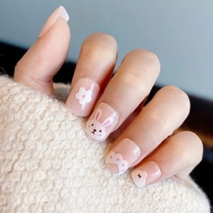 Close-up of nude press-on nails featuring cute pink rabbit and white flower designs