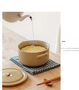 Steaming hot water pouring into a beige ceramic noodle bowl with lid and double handles
