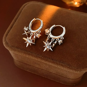 Detailed view of silver hoop earrings featuring star pendants with sparkling zircons